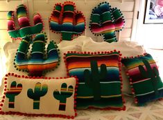 colorful pillows with cactus designs and pom poms on them