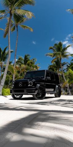 a black suv parked on the beach near palm trees