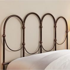 an iron headboard with four curved posts on the top and bottom, against a white wall