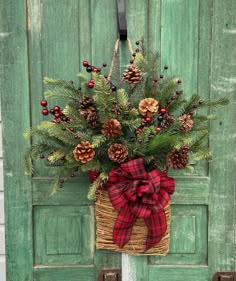 a basket with pine cones and berries hanging on a green door