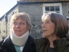 two women standing next to each other in front of a building with a sky background