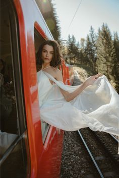 a woman in a white dress leaning out the window of a train