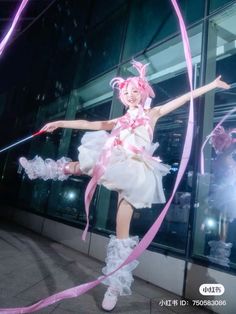 a woman dressed in white and pink is dancing with streamers around her legs while another person looks on