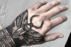 a person's hand with a tattoo on it and a moth on the wrist