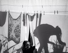 a woman is standing in front of some curtains with the shadow of a cat on it