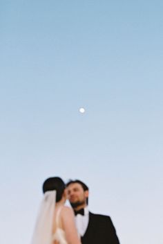 the bride and groom are looking at each other in front of the moon on their wedding day