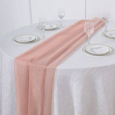 the table is set with white plates and silverware, along with pink napkins