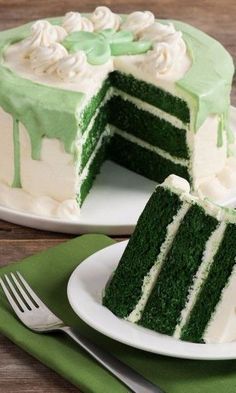 there is a green cake with white frosting on the top and one slice missing