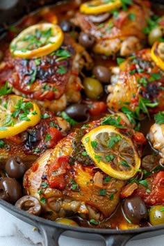 a skillet filled with chicken, olives and lemon slices