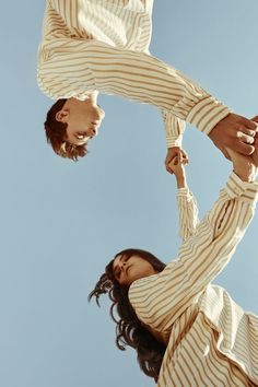 two people standing in the air with their arms around each other and looking up into the sky