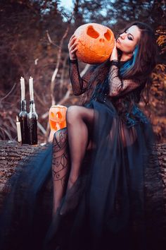 a woman in a black dress holding an orange pumpkin