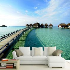 a living room with an ocean view wallpapered in blue and green water, along with white couches