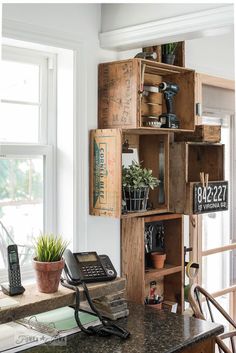 a phone is sitting on a desk in front of a window with wooden crates holding plants