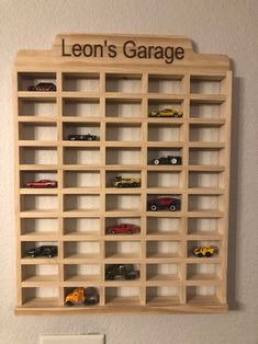 a wooden shelf with cars on it and the words leon's garage above it