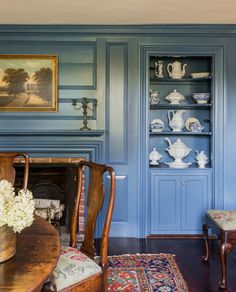 a living room with blue walls and wooden furniture in the corner, along with an antique fireplace