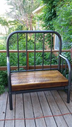 a wooden bench sitting on top of a wooden deck next to green bushes and trees