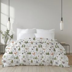 a bed covered in white sheets with forest animals on them