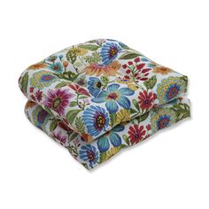 two pillows with colorful flowers on them sitting next to each other in front of a white background