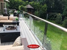 an outdoor deck with furniture and trees in the backgroung area, overlooking a lush green yard