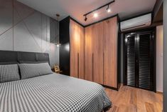 a bedroom with a bed and wooden floors in front of a wall mounted air conditioner