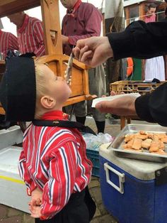 a small child is getting food from an adult