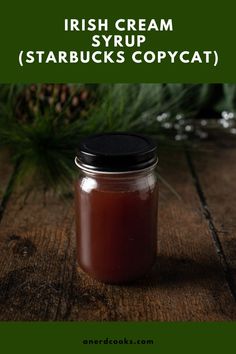 a jar filled with syrup sitting on top of a wooden table next to pine cones