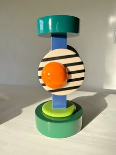 a colorful object sitting on top of a green and yellow stand next to a white wall