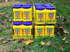 four yellow containers with blue lids sitting in the grass