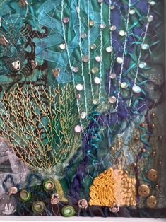 an art work with buttons and beads on the bottom, surrounded by seaweed and corals