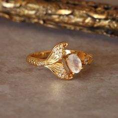 Elevate your style with the Sirena Ring, a gentle homage to the ocean's mystical allure. Designed for the girl who cherishes the sea, this elegant piece features a natural moonstone center stone, gracefully complemented by a delicate mermaid tail and intricate barnacle accents. Embrace your inner mermaid with this exclusive ring, offering a serene blend of whimsy and sophistication. Mermaid Rings Engagement, Mermaid Inspired Jewelry, Ocean Inspired Rings, Mermaid Engagement Ring, Mermaid Rings, Sea Rings, Sea Inspired Jewelry, Ocean Ring, Mermaid Vibes