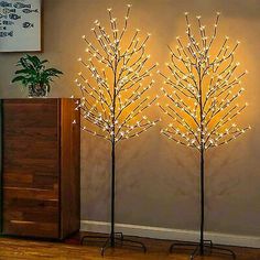 three lighted trees in the corner of a room