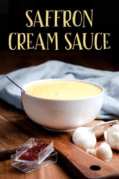 a bowl of saffron cream sauce on a cutting board next to garlic and cloves