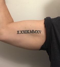 a man's arm with roman numerals tattooed on the upper half of his arm