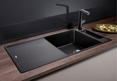 a black kitchen sink sitting on top of a counter next to a plate of food