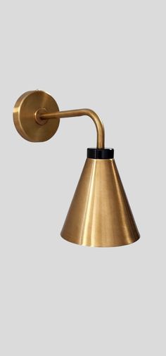 a brass wall light with a black handle on the side and a white back ground