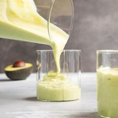 someone is pouring something into a glass on the table next to some other food items