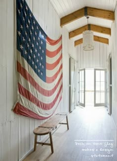 an american flag hanging on the wall next to a bench in a room with white walls