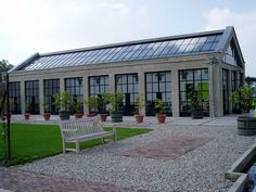 a white bench sitting in front of a building with lots of windows and potted plants