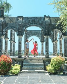 two people standing on steps in front of an archway