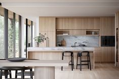 a kitchen with wooden cabinets and stools next to a counter top that has two black bar stools in front of it