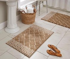 two bathroom rugs on the floor in front of a sink and toilet with slippers