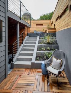 a chair sitting on top of a wooden floor next to a stair case and planter