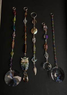 five different necklaces are hanging on a black surface, one has an owl charm