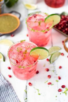 two glasses filled with pink lemonade, lime and pomegranate garnish