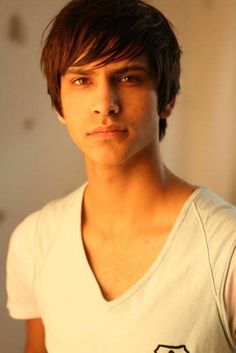 a young man in a white shirt looking at the camera