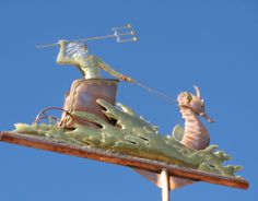 a weather vane on top of a building with a sea horse