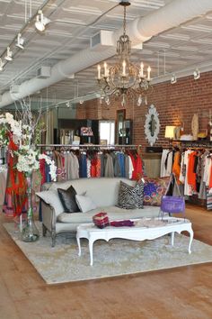 a living room filled with furniture and lots of clothes hanging on the racks in front of it