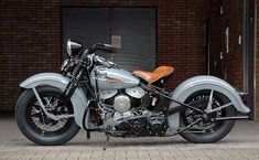 a silver motorcycle parked in front of a brick building