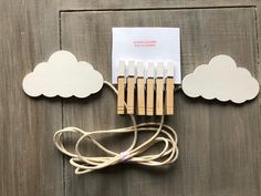 a bunch of clothes pins sitting on top of a wooden table next to paper clouds