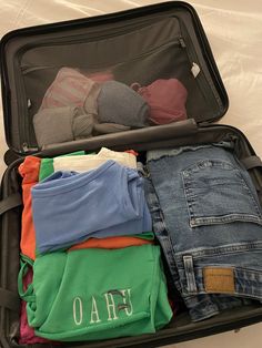 an open suitcase filled with clothes and t - shirts